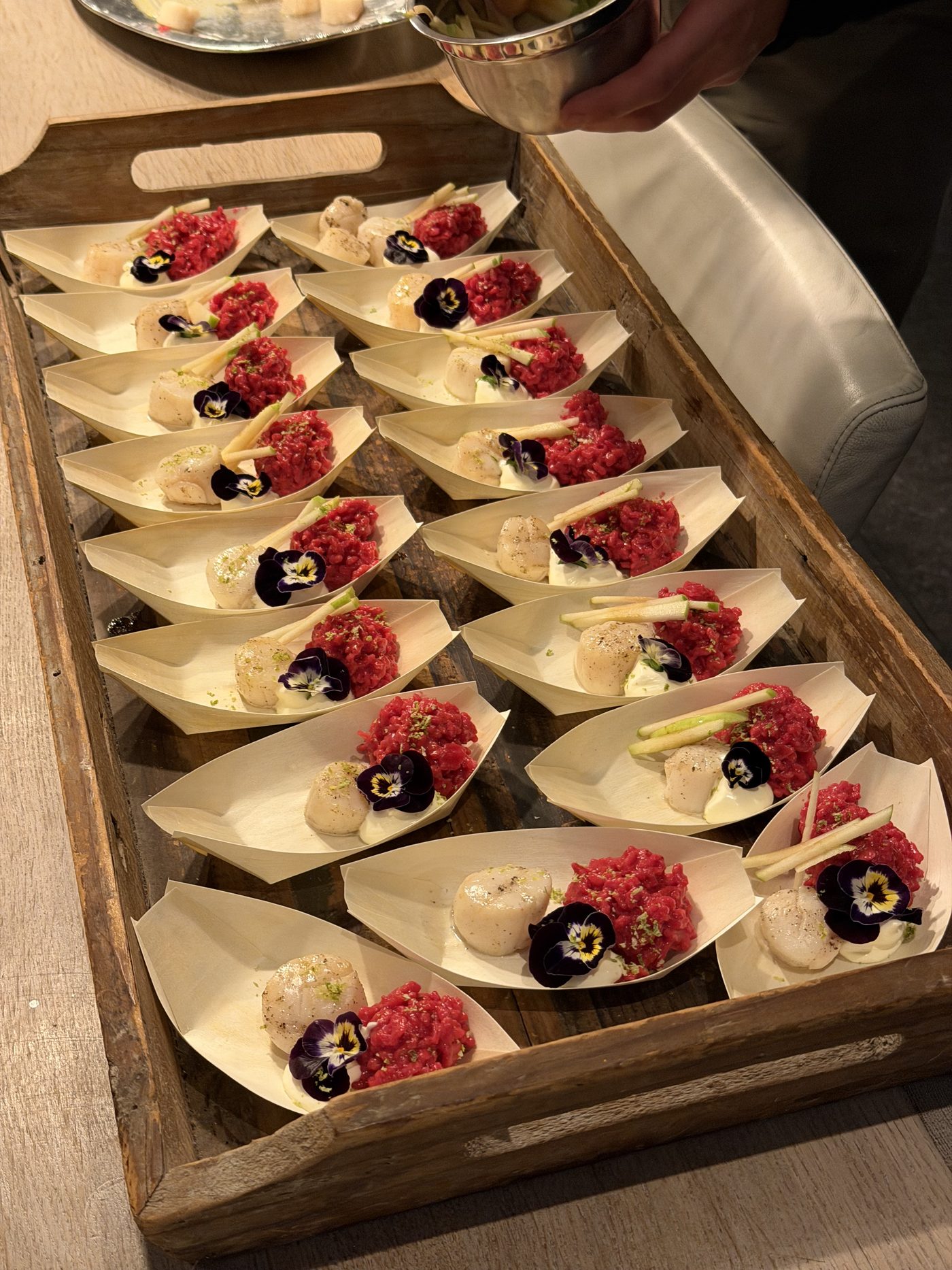 Dienblad met luxe hapjes: steak tartaar en coquille in houten bakjes