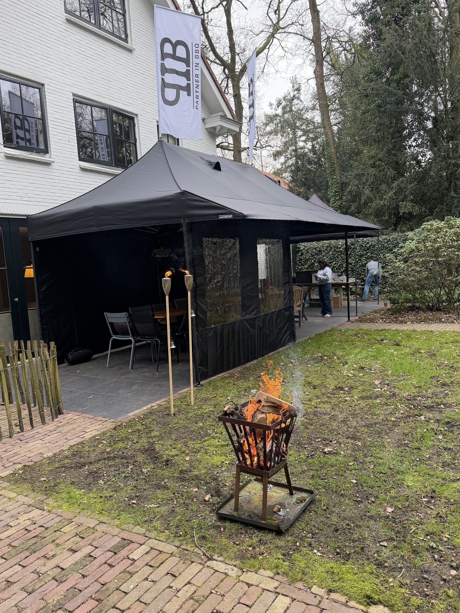 Zwarte Partner in BBQ tent met vlaggen en vuurkorf in een tuin